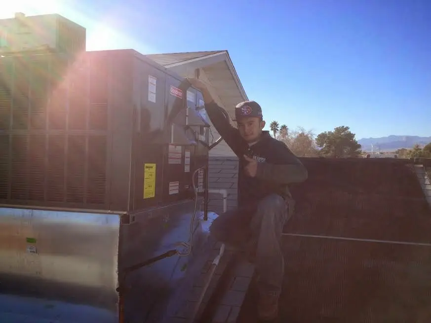 HVAC technician performing AC Tune-Up on a rooftop unit in Antigo